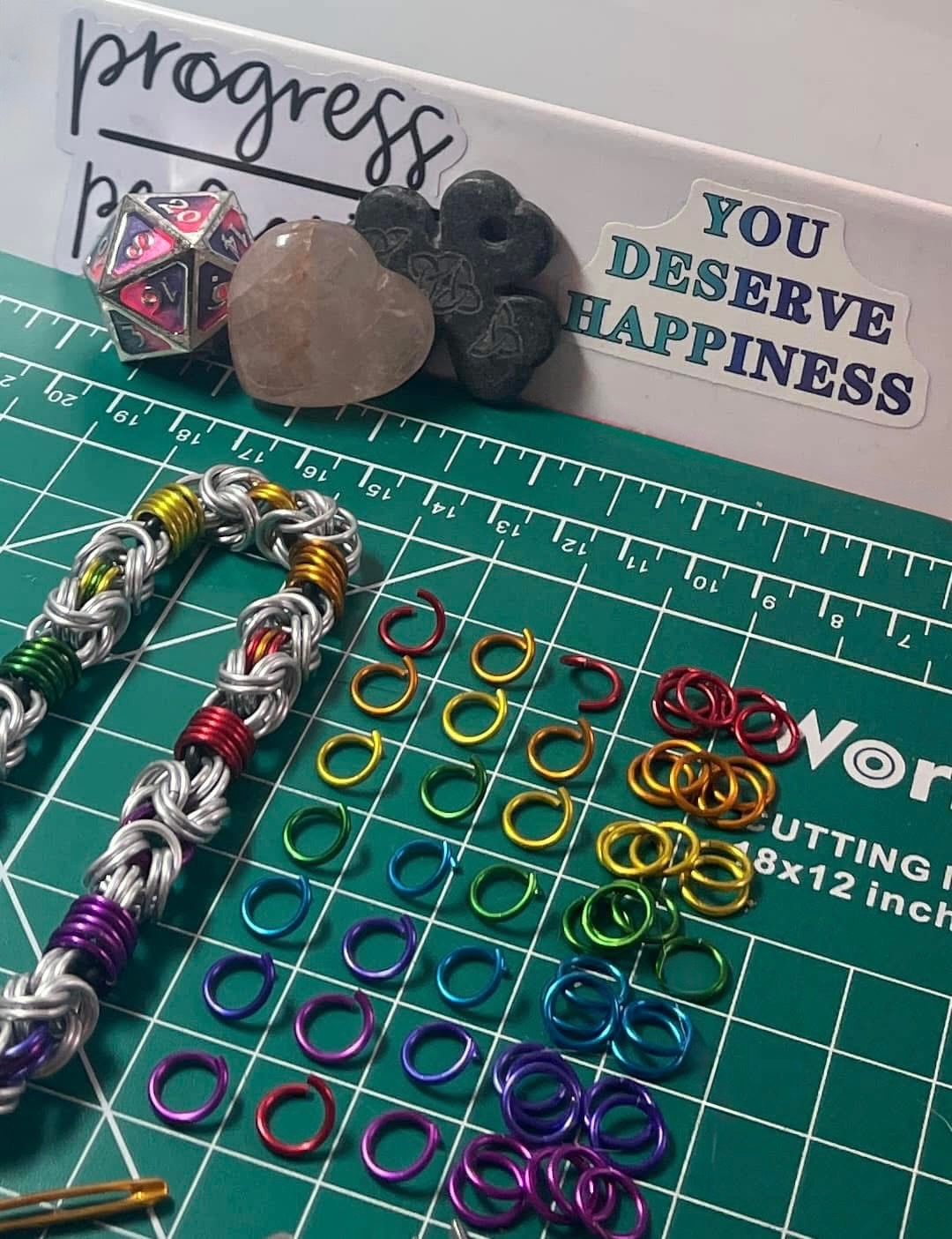 Close view of chainmaille making tools and jump rings on a tabletop.